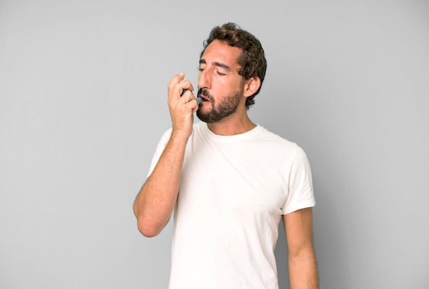 Młody szalony brodaty i ekspresyjny mężczyzna z inhalatorem na astmę