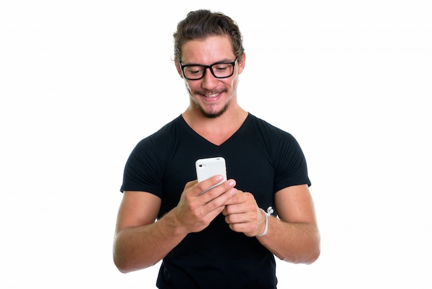 Młody szczęśliwy mężczyzna ono uśmiecha się podczas gdy używać telefon komórkowego