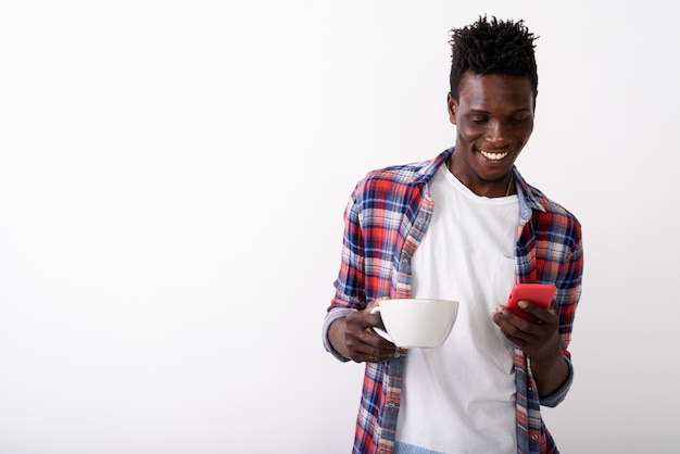 Młody szczęśliwy mężczyzna uśmiecha się filiżankę kawy i smartphone i trzyma