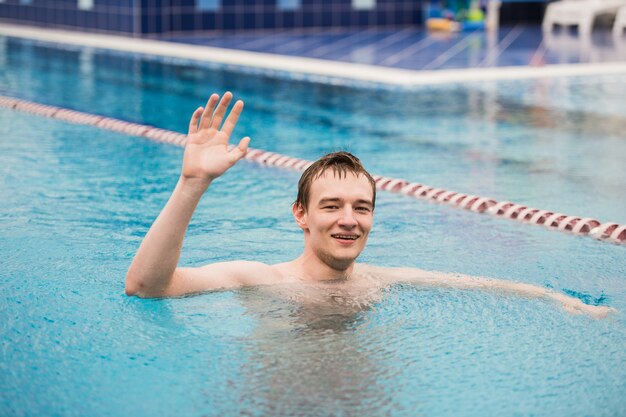 Młody Szczęśliwy Mężczyzna W Pływackim Basenie Gestykuluje Kciuk Up
