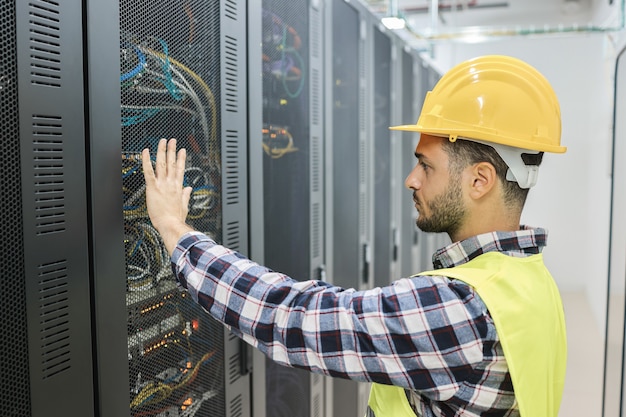 Zdjęcie młody technik pracujący z tabletem w pokoju dużego centrum danych - skup się na twarzy mężczyzny