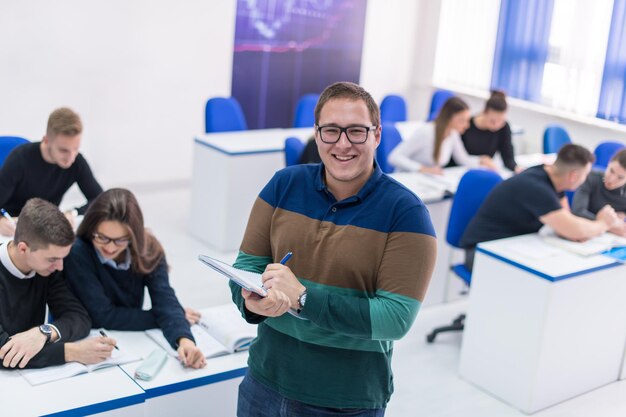 młody uczeń płci męskiej z innymi piszącymi notatki w klasie