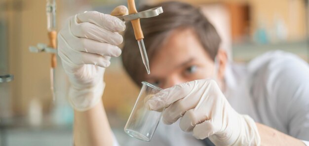 Młody uczeń przeprowadza testy chemiczne w szkole ze szklanymi kolbami b
