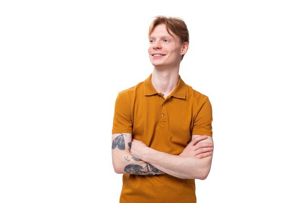Zdjęcie młody, udany, rudy facet ubrany w pomarańczową koszulkę z tatuażem na ramieniu.