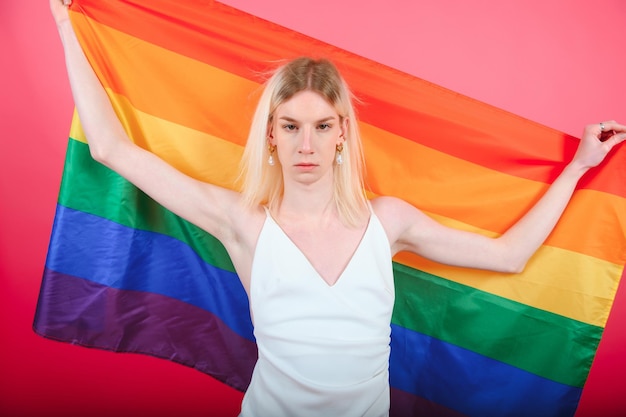 Młody wesoły 20s z makijażem zawinięty w tęczową flagę w paski na białym tle na tle portretu studyjnego ludzie styl życia moda koncepcja lgbtq