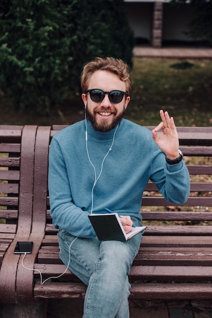 Młody wesoły hipsterski chłopiec zauważa pomysły siedzące w parku