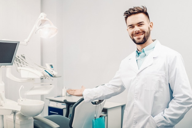 Młody wesoły męski dentysta w gabinecie dentysty