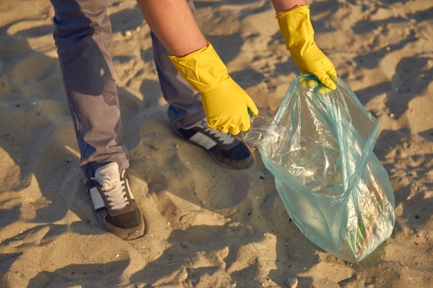 Młody Wolontariusz W żółtych Rękawiczkach Spaceruje Z Workiem Na śmieci Po Brudnej Plaży Nad Rzeką