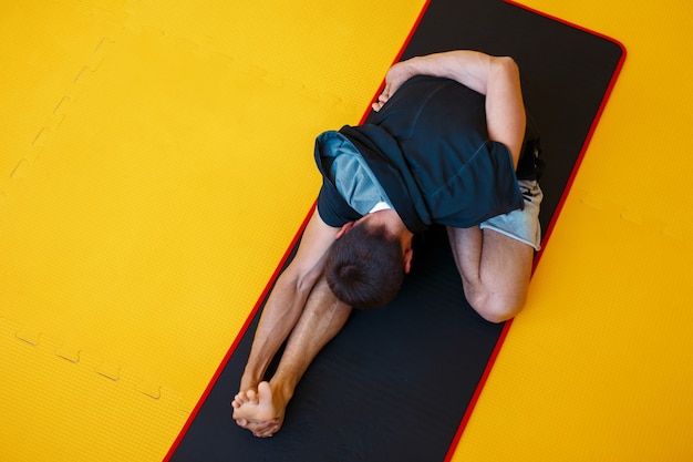 Młody zdrowy facet robi ćwiczenia na siłowni na żółtej podłodze