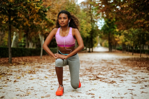 Młody żeński biegacz z piękną postacią robi rozciągania ćwiczeniu przed jogging.