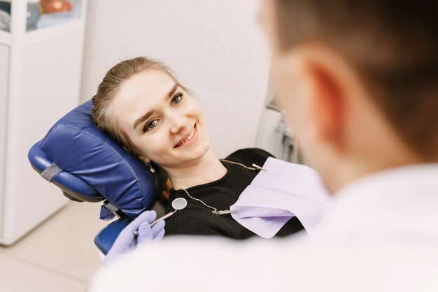 Młody żeński obsiadanie w dentysty biurze i patrzeć jej lekarkę z uśmiechem. Kobieta przyszła do dentysty. Szczęśliwy pojęcie pacjenta i dentysty
