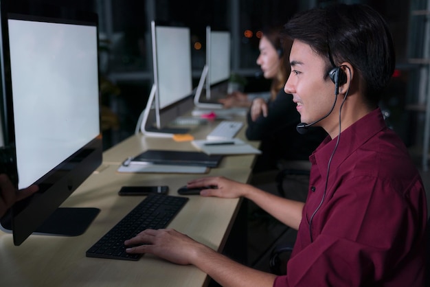 Młodzi azjatyccy operatorzy obsługi klienta pracujący w nocnej zmianie w call center