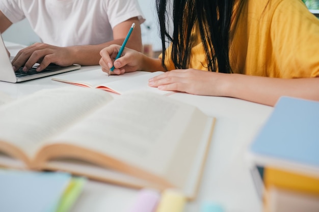 Młodzi azjatyccy studenci czytają razem z przyjaciółmi, uczą się razem z przyjaciółmi