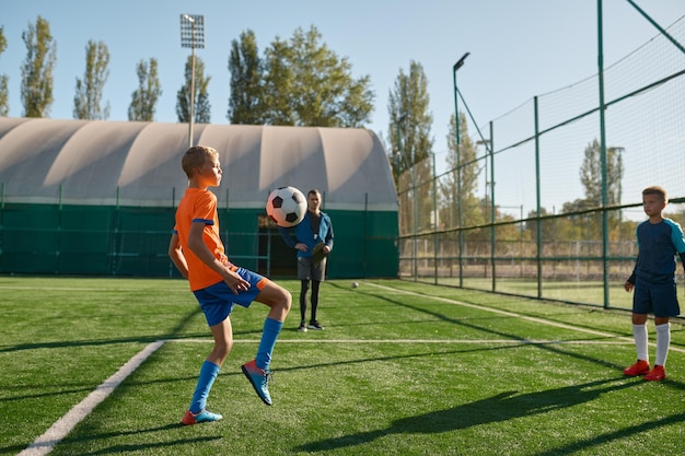 Młodzi chłopcy grający w mecz piłki nożnej na obozie treningowym dla dzieci. Turniej sportowy dla drużyny młodzieżowej w lecie