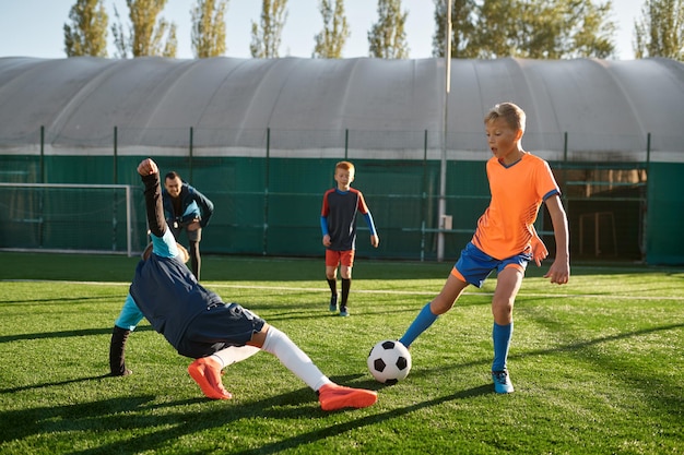 Młodzi chłopcy grający w piłkę nożną podczas zawodów juniorów w szkole sportowej. Mecz finałowy turnieju piłki nożnej dla dzieci