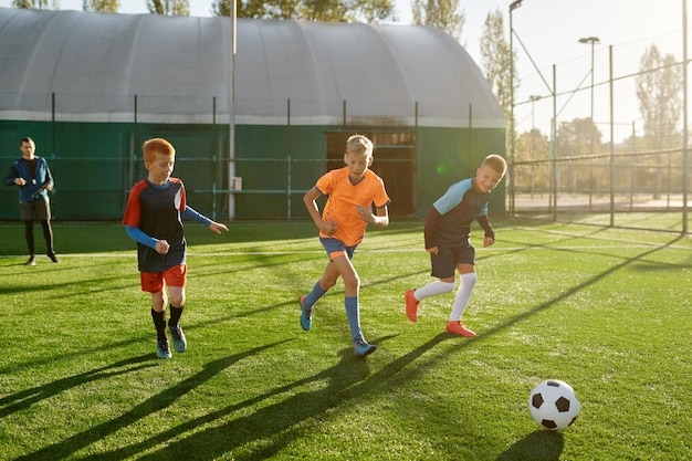 Młodzi chłopcy w sportowym klubie piłkarskim na jednostce treningowej doskonalącej umiejętności na boisku z trawą naturalną