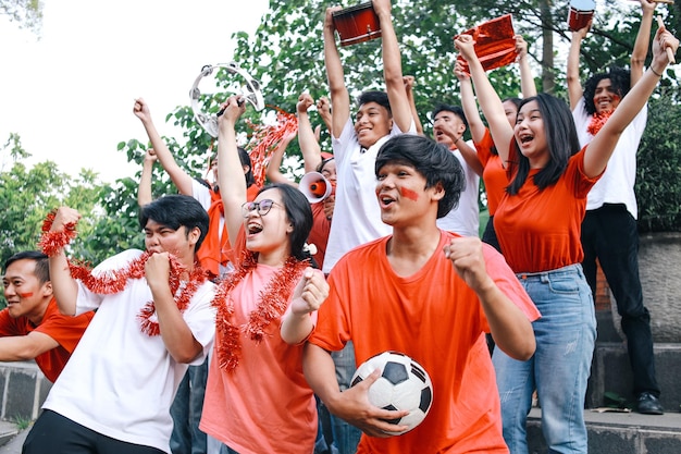 Młodzi ludzie bawiący się wspierając ulubiony klub Fani piłki nożnej oglądający mecz piłkarski