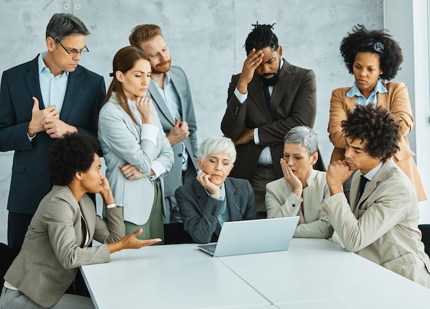 Młodzi ludzie biznesu spotykają się w biurze problem pracy zespołowej stres zmartwiony grupowa różnorodność korporacyjna starszy dojrzały kolega laptop komputer frustracja smutny myślenie poważne
