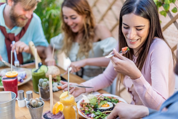 Młodzi ludzie je brunch i pije smoothie rzucają kulą przy rocznika barem. Szczęśliwi ludzie jedzący zdrowy lunch i rozmawiający w modnej restauracji