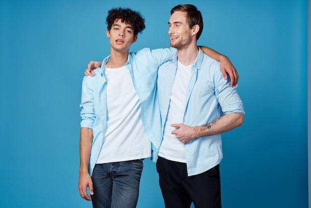 Młodzi mężczyźni w niebieskich koszulach przytulający się na odosobnionej zabawie przyjaciół tła