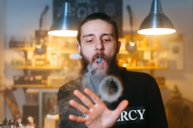 Zdjęcie młodzi mężczyźni z brodą vaping i uwalniają chmurę pary zbliżenie