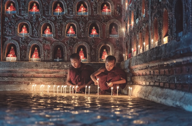 Młodzi nowicjuszi michaelita zaświeca w górę blasku świecy wśrodku Buddyjskiej świątyni, niskiego światła położenie, shanu stan, Myanmar.