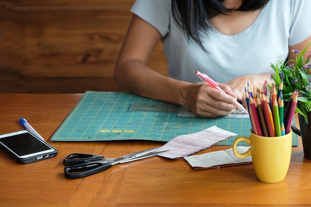 Młodzi projektanta mody pracujący ubrania na drewnianym stole.