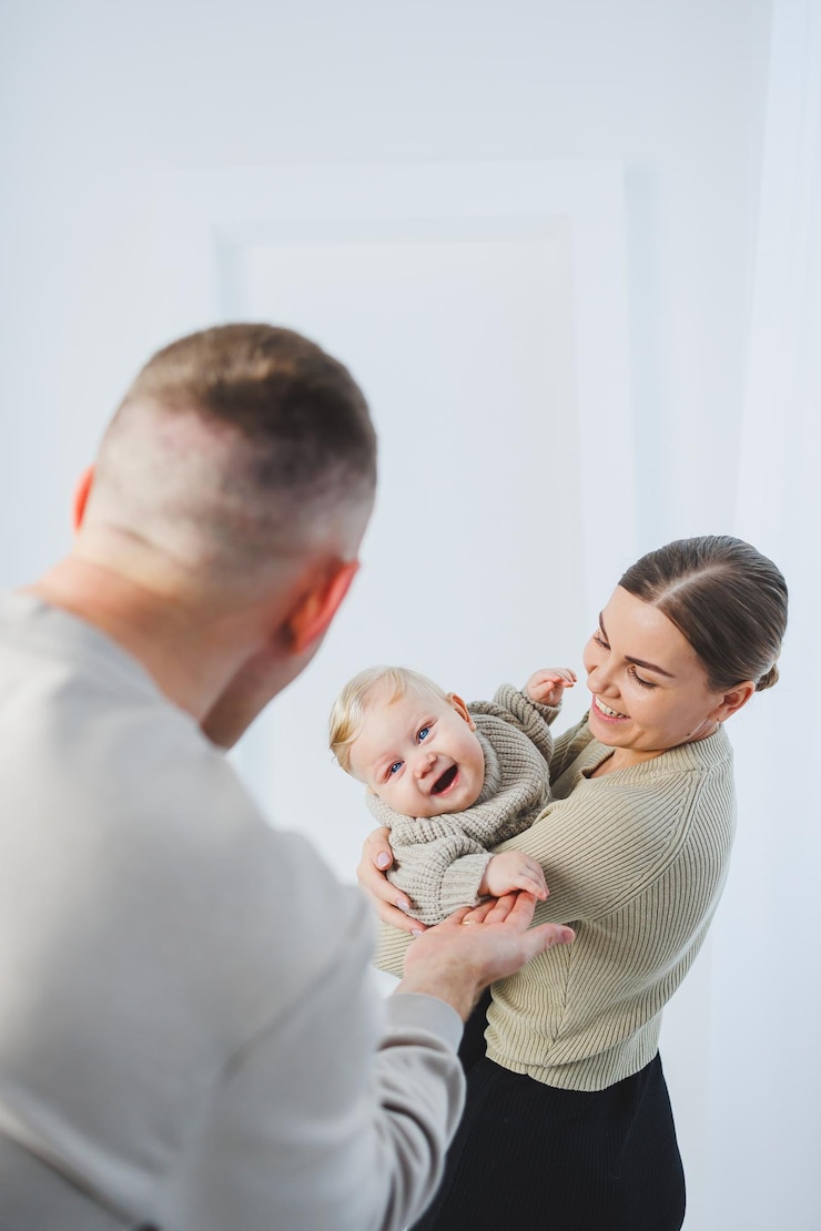 Zdjęcie młodzi rodzice, mama i tata, bawią się z dzieckiem na białym tle.