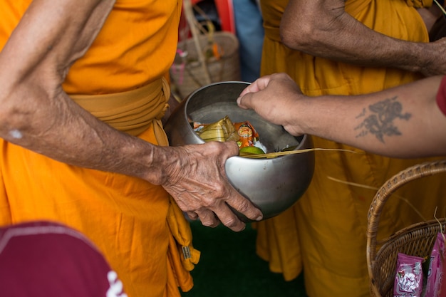 Mnisi buddyjscy otrzymują ofiary żywnościowe od ludzi na koniec buddyjskiego dnia Wielkiego Postu