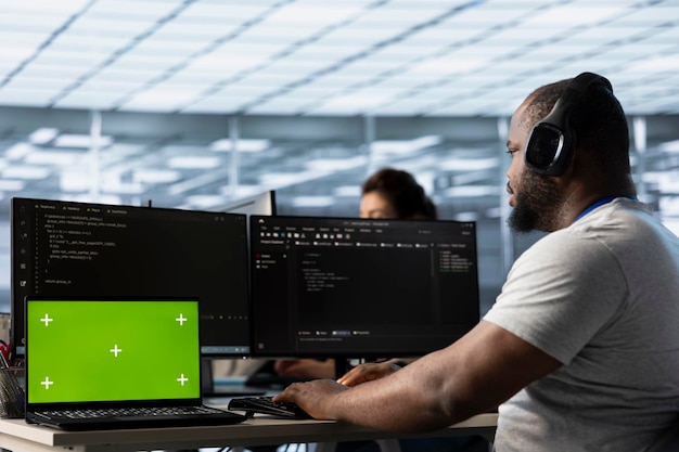 Mockup laptopa przed pracownikami wsparcia IT kodującymi słuchającymi muzyki