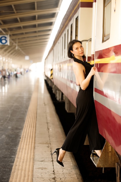 Moda azjatycka kobieta nosić czarną luksusową sukienkę. Model LGBT Transgender podróżuje pociągiem na stacji kolejowej. Koncepcja po postu Covid
