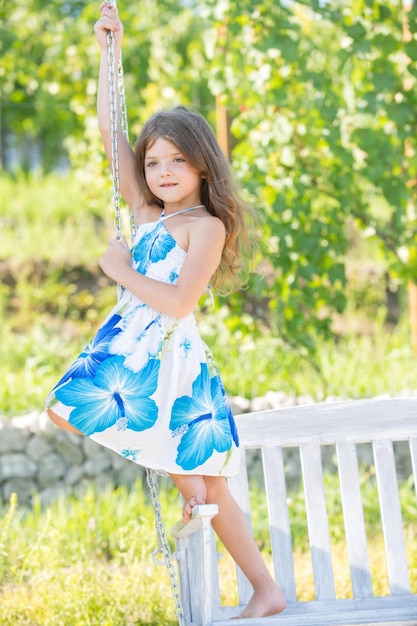 Moda dla dzieci ubiera się szczęśliwe małe dziecko dziewczynka na huśtawce w letnim parku marzycielskie dzieci twarzą w twarz mały chi