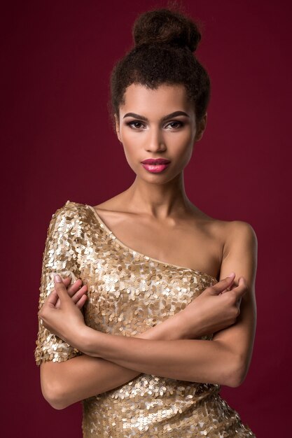Moda młoda afrykańska kobieta z makijażem w seksownej złotej sukience