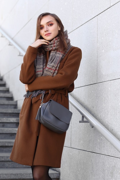 Moda młoda kobieta na zewnątrz na sobie płaszcz, szalik i torebkę