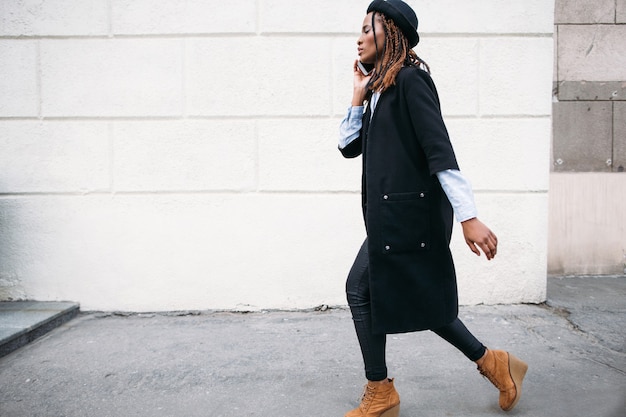 Moda piesza. Nowoczesna komunikacja społeczna. Stylowa czarna kobieta na białym tle, model afroamerykański, koncepcja technologii