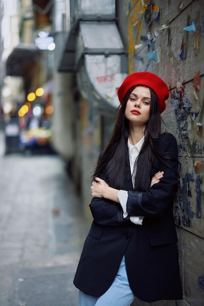 Moda portret kobiety spacerujący turysta w stylowych ubraniach z czerwonymi ustami idąc wąską ulicą miasta podróż kinowy kolor retro styl vintage dramatyczny na tle ściany z graffiti