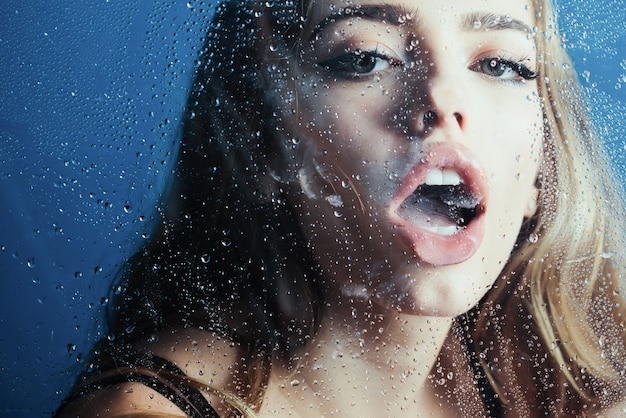 Moda uroda i miłość okno z kroplami wody przed zmysłowa dziewczyna krople deszczu na szybie w kształcie serca seksowna kobieta za oknem z kroplami wody