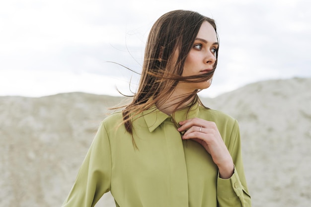 Moda uroda portret młodej kobiety z długimi włosami w zielonej koszuli ekologicznej na tle pustyni