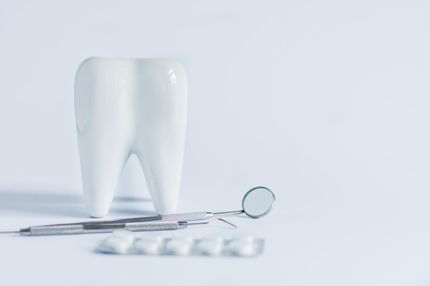 Model białych tabletek medycznych i narzędzi stomatologicznych na białym tle