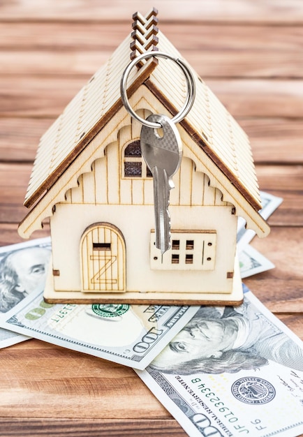 Model dom z dolarowymi rachunkami i kluczem na drewnianym tle