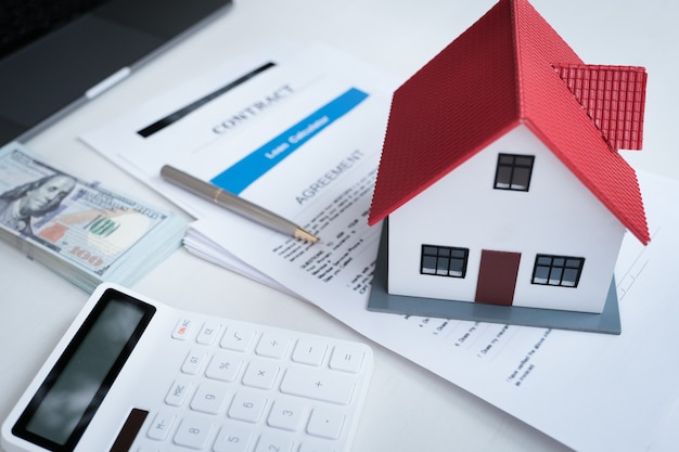 Model domu, dokument nieruchomości, umowa, umowa pożyczki, ubezpieczenie i kalkulatory na stole