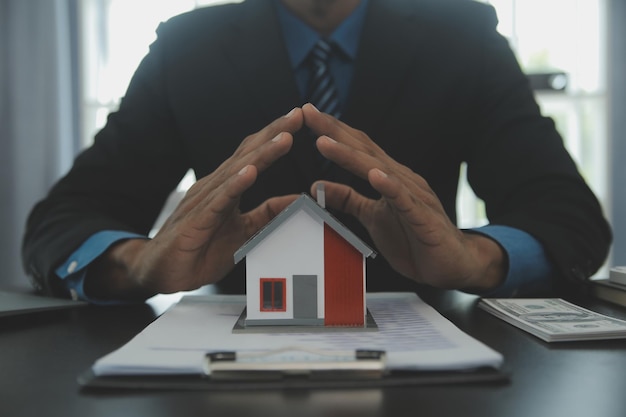 Model domu z agentem nieruchomości i klientem omawiającym umowę na zakup ubezpieczenia domu lub pożyczkę koncept nieruchomości
