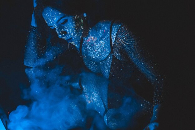 Model kobiety w świetle neonowym piękna modelka dziewczyna z fluorescencyjnym makijażem artystycznym projekt Niebieskie zdjęcie przyciemniane Koncepcja zdjęcia morskiego Cosplay awatar