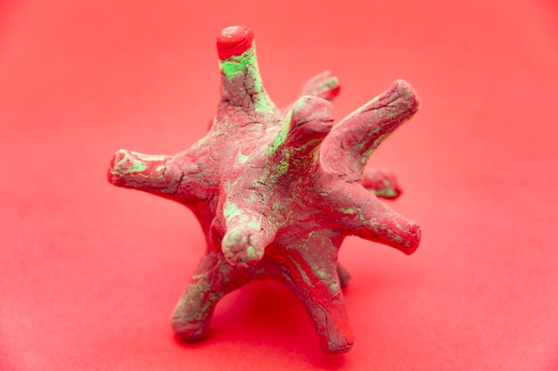 Model Koronawirusa Wykonany Z Czerwonej I Zielonej Plasteliny Na Czerwonym Tle