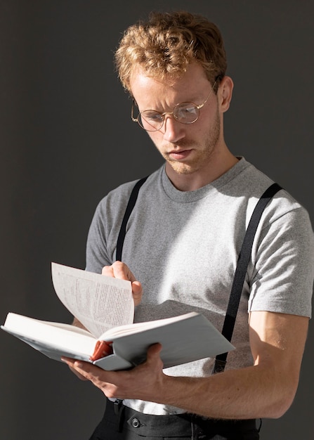 Model mężczyzna ubrany w szelki akcesoria i czyta