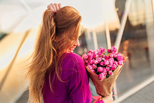 Model piękna dziewczyna z długimi włosami i piękne różowe róże. Moda kobieta z prostymi, zdrowymi włosami