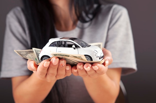model samochodu i dolary w kobiecej dłoni