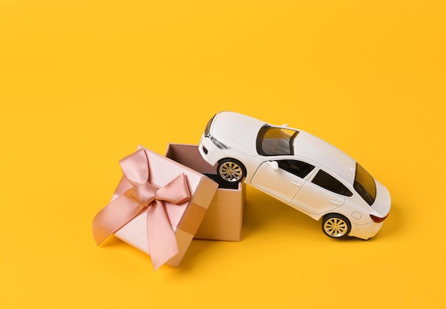 Zdjęcie model samochodu zabawkowego z pudełkiem podarunkowym na żółtym tle