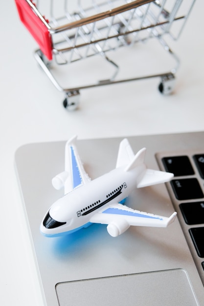 Zdjęcie model samolotu stoi na laptopie obok wózka. zakup biletów na lot przez internet.