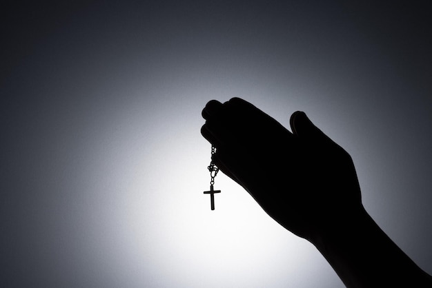 Modlące się ręce trzymające różaniec Zbliż się trzymając naszyjnik z krzyżem modlić się o boga w ciemności religijny chrześcijański symbol z kopiowaniem przestrzeni w tle Bóg i duchowe pojęcia